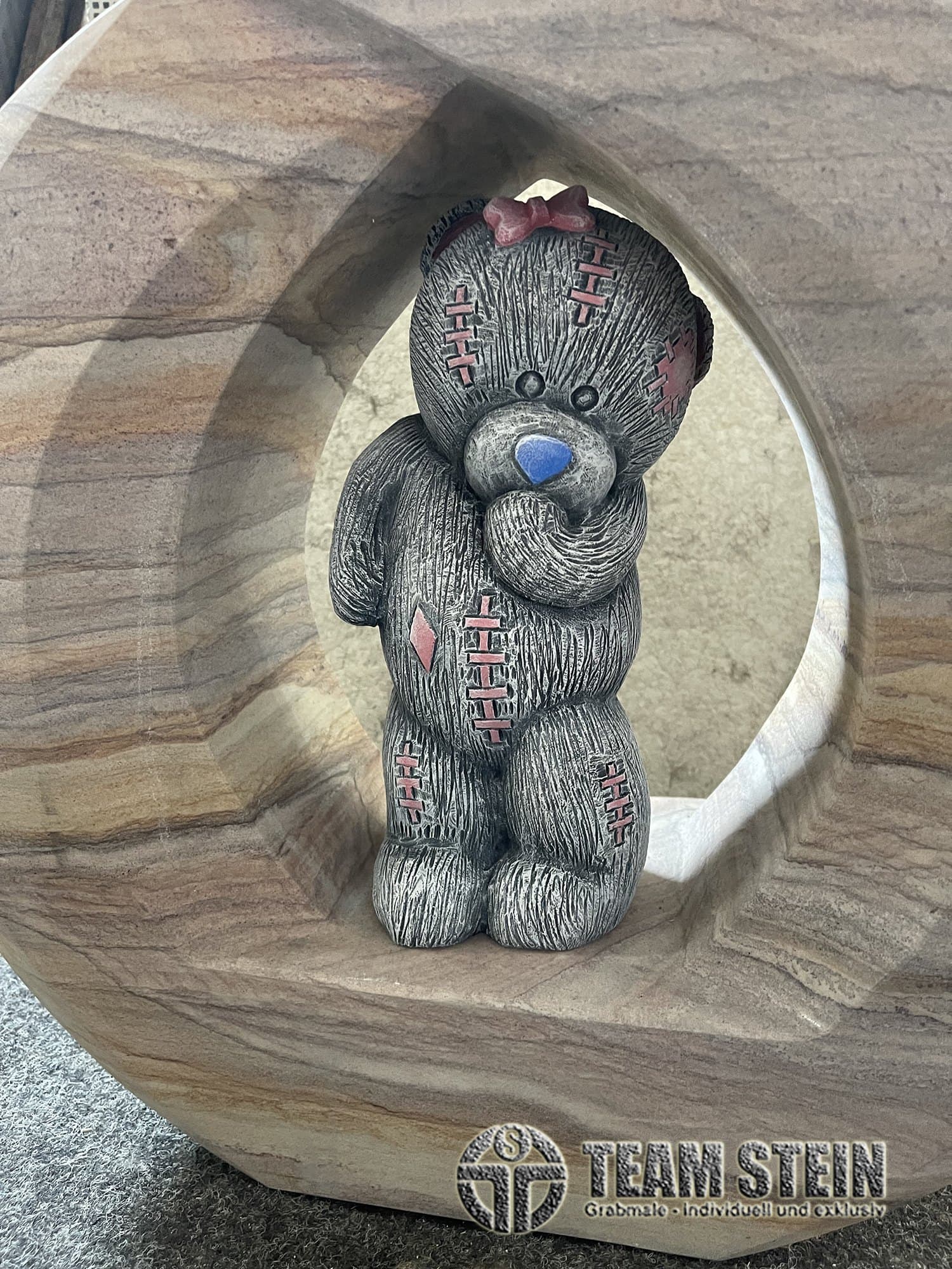 Teddybär-Figur aus Stein in einem Rund aus gemasertem Sandstein