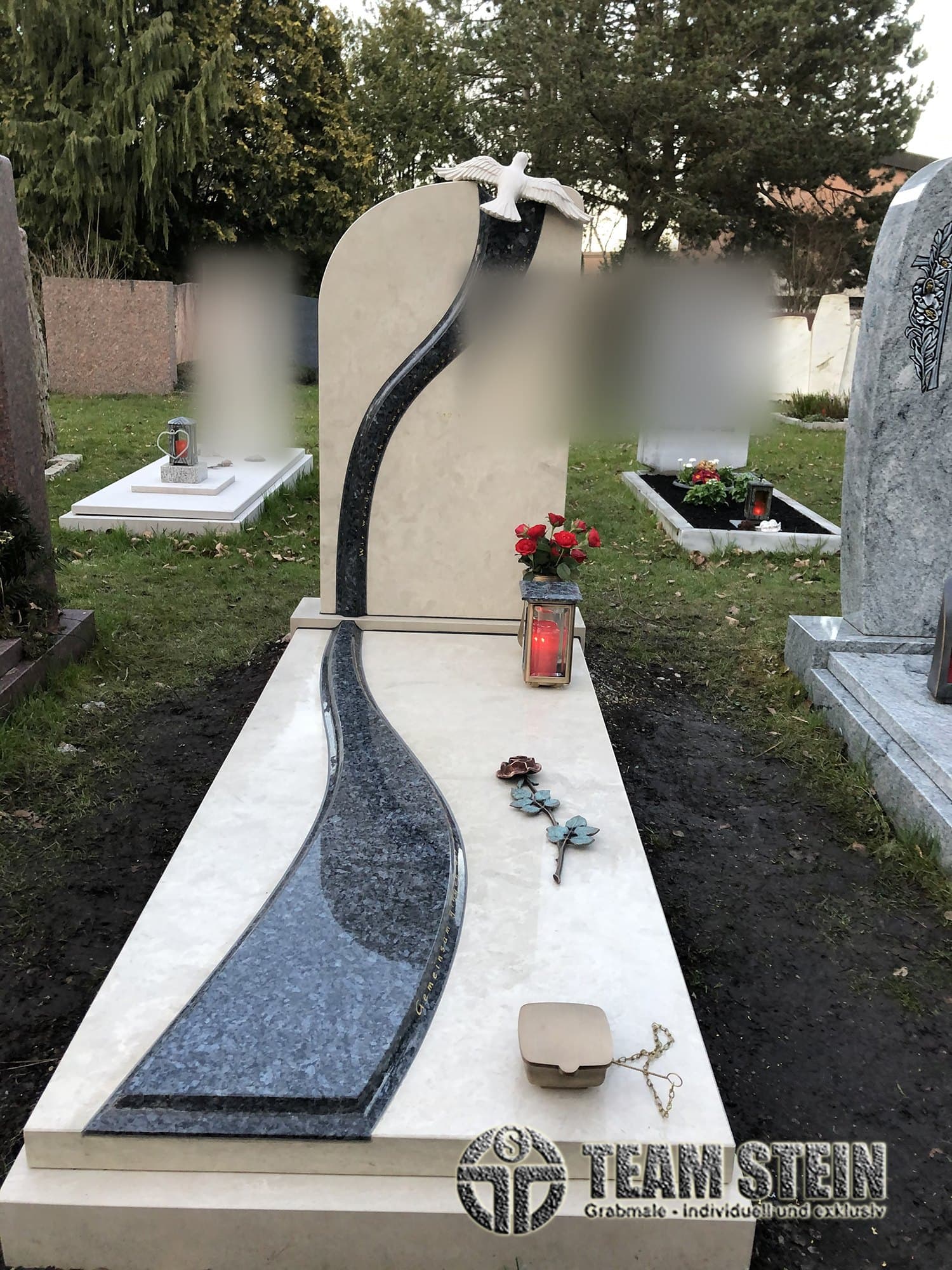 Grabmal aus hellem Stein mit geschwungenem blauem Granitband und einer Taube oben