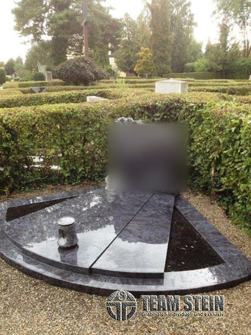 Halbrunde Grabanlage aus dunklem, poliertem Granit mit Pflanzflächen und Vase